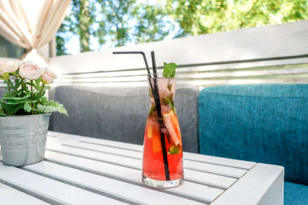 A cold lemonade of fresh tropical fruits. Red cocktail on table in street cafe.