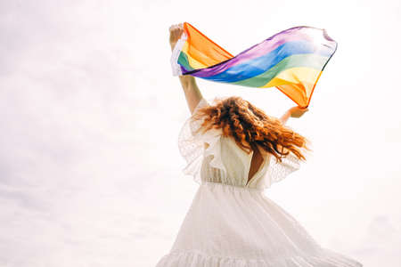 Lesbian woman with rainbow flag on sunny sky background. LGBTQ concept.の写真素材