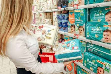 Perm, Russia - July 27 2021: Young woman in the store chooses diapers.