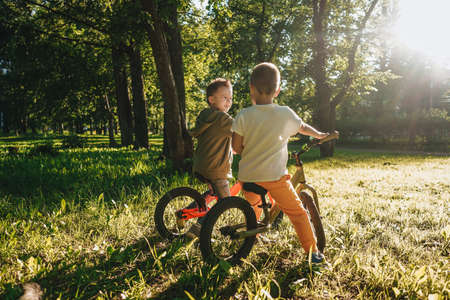 Two little boys riding their balance bikes in park.の写真素材