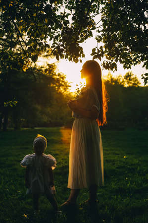 Mother and little daughter in Sunset light, spring concept. Profile view, defocused.