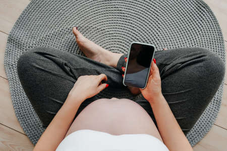 Pregnant woman with a phone in her hands, top view. Online shopping concept.の写真素材