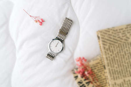 Silver watch on white textile top view. Dry branch of flowers and books as decoration.の写真素材