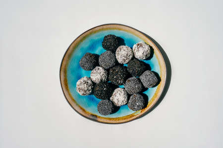 Homemade date candies covered with poppy, sesame and shredded coconut. Top view, white background.の写真素材