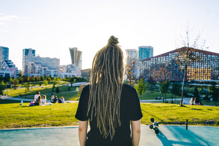 Rear view young woman with dreadlocks in park.の写真素材