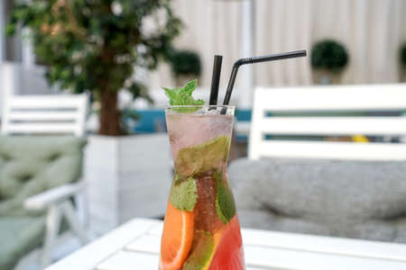 A cold lemonade of fresh tropical fruits. Red cocktail on table in street cafe.の写真素材