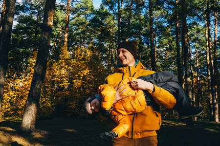 Father and son having fun in autumn forest. The man tickles the boy and he laughs.の写真素材