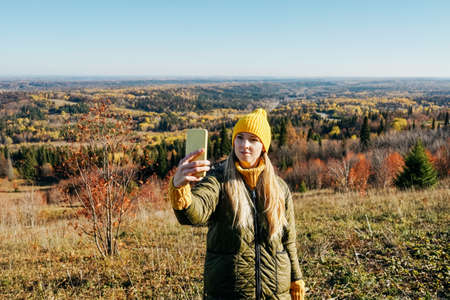 Young woman takes selfie on autumn landscape. Mountain travel.の写真素材