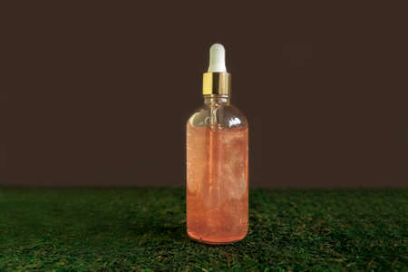 Blank glass face serum bottle on green and brown background. Copy space.の写真素材