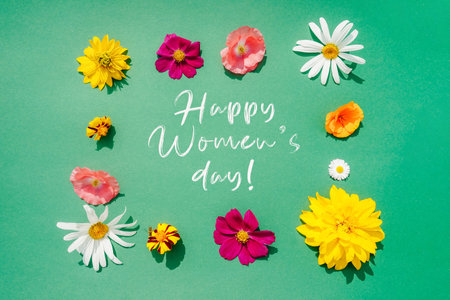 Flowers frame composition on green background with text Happy women's day. Flat lay, top view.の写真素材