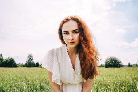 Portrait of young beautiful smiling woman in the field. Glitter on face.