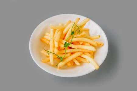 French fries on plate on gray background. Close-up, front view.
