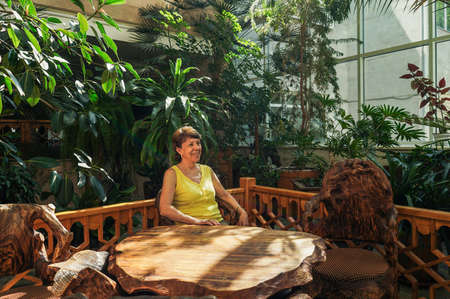 Senior Woman relax in botanical garden. Green plants around, sustainable design.の写真素材