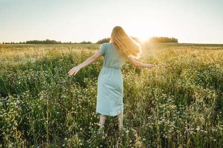 Woman dance in the field on sunset. Defocused, grass on foreground.の写真素材