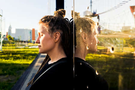Young happy woman with dreadlocks in park. Modern mirror building on background.の写真素材