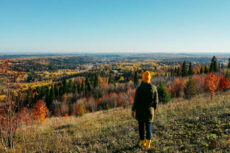 Young woman in yellow green clothes standing in mountain. Rear view.の写真素材