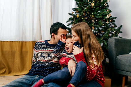 Happy family sitting on floor near Christmas tree.の写真素材