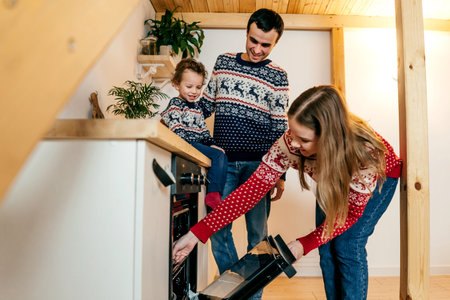 Happy family in christmas sweaters in kitchen.の写真素材