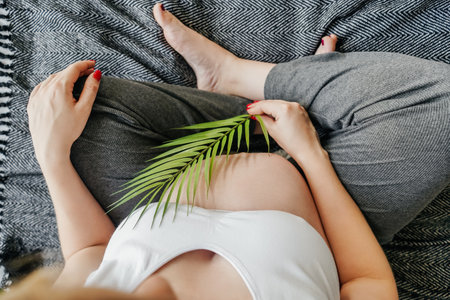 Pregnant woman holding palm leaf, top view.の写真素材