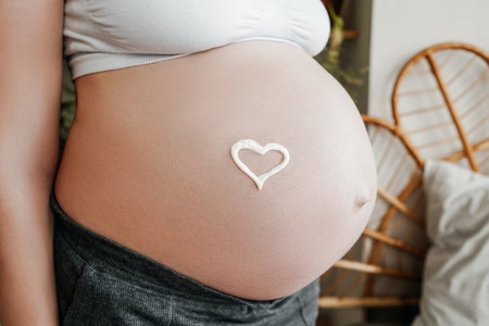 Pregnant woman close-up. Belly with red heart.
