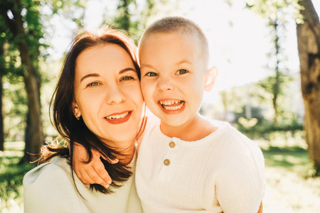 Mother and little son portrait in the park. Summer lifestyle portrait, sun on background.の写真素材
