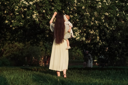 Mother and little daughter near blooming apple tree.の写真素材