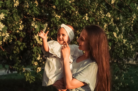 Mother and little daughter near blooming apple tree.の写真素材