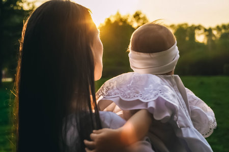 Mother and little daughter rear view. Sunset light.の写真素材