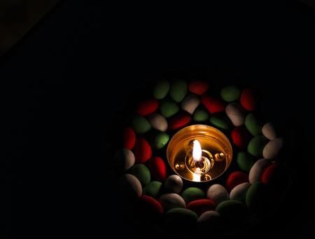 candle fire at night surrounded by colored stones in blurの写真素材