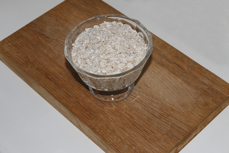 oat flakes in a bowl on a wooden stand on white backgroundの写真素材