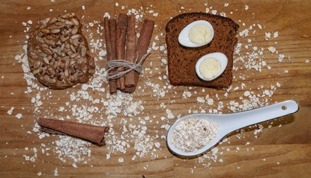 quail eggs on a black bread and oat chips and cookie and a cinnamon stick on a wooden table