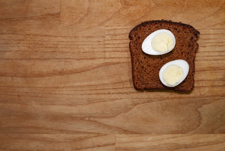 quail eggs on a black bread on a broun wooden table top view