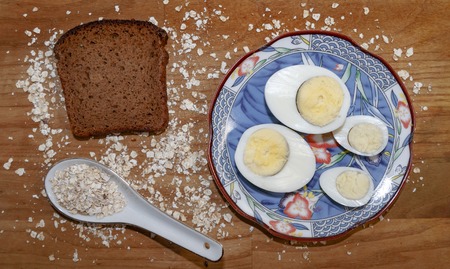 chicken and quail eggs on a blue saucer and oat chips and a piece of black bread on a wooden table
