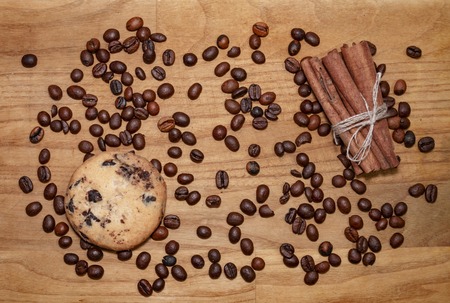 cookie and cinnamon stick and coffee beans on a broun wooden table top viewの写真素材