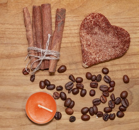 cookie and cinnamon stick and coffee beans and candle on a broun wooden table top view