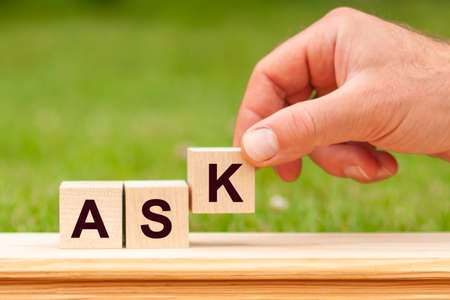 The inscription ASK on wooden blocks on green background. Letter text on wooden cube.の写真素材