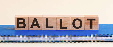 BALLOT Word written on wooden blocks black font on background blu notepad.の写真素材