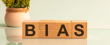 The word BIAS message word on a wooden desk on cube blocks with a flower on background.の写真素材
