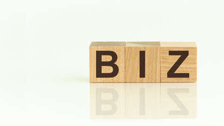 Wooden Blocks with the text: BIZ. The text is written in black letters and is reflected in the mirror surface of the table. New business relaunch startup conceptの写真素材