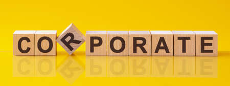 corporate word written on wood block. corporate text on table, concept. Word corporate is made of wooden building blocks lying on the table and on a light yellow background.の写真素材