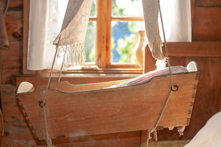 an old cradle in the house of a Forester of the 20th century. Suspended from the ceiling against the background of a window