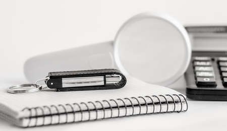 A white magnifying glass and a white pen are on the Notepad. In the background is a calculator