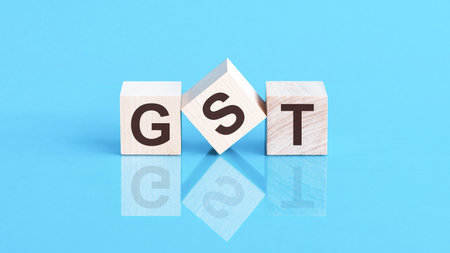 GST - Goods and Service Tax - word is made of wooden building blocks lying on the blue tableの写真素材