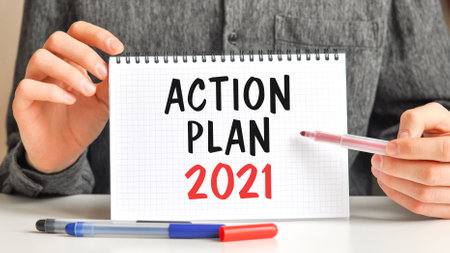 A sheet of paper with text ACTION PLAN 2021, multicolored markers on a white table. Business and educational concept.の写真素材