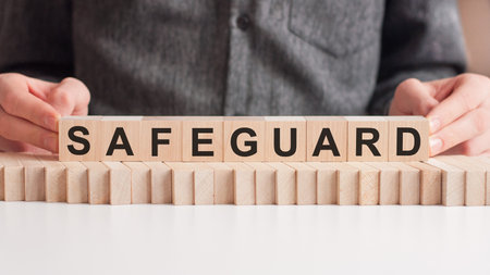 The hand puts a wooden cube with the letter SAFEGUARD. The word is written on wooden cubes standing...