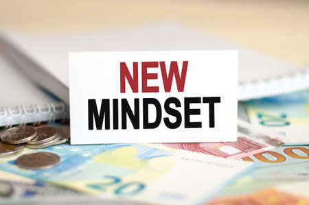 Finance and economics concept. On the table are bills, a bundle of dollars and a sign on which it is written - NEW MINDSETの写真素材