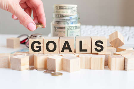 the word Goals on the wooden blocks and a bank with money in the background, business conceptの写真素材