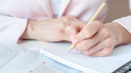 a woman writes down information with a pen in a diary
