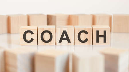 the word COACH is written on a wooden cubes structure. Blocks on a bright background. Can be used for business, education, financial concept. Selective focus.の写真素材