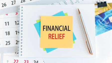 financial relief, the text is written on yellow paper lying on a white notepad on the desktop of an office employee, conceptの写真素材